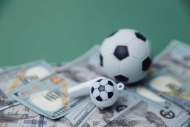 Futbol Dünyası Konsepti. Dolar banknotları ve yeşil arka planda top ve ıslık. Futbol kumar para konsepti