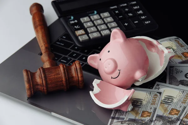 Broken piggy bank, cash and wooden gavel on keyboard. Business and bankruptcy concept