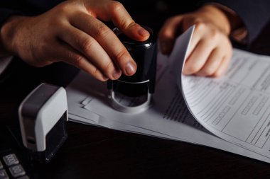 İşadamı kâr sözleşmesini onaylıyor. Para yığını, kontrat ve pullar masanın üstünde. İş ve para kavramı