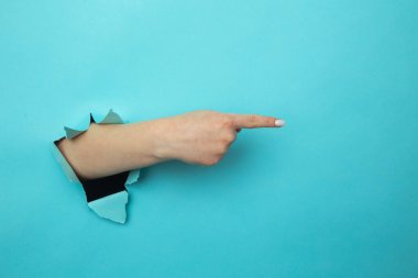 Kadın, kağıt mavisi duvarın içinden kolunu kırıyor. Bu da boş bir alanda olduğunu gösteriyor. Tavsiye veriyor. Reklamınız için yer