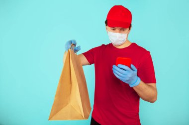 Yemek teslimatı konsepti. Kırmızı elbiseli bir kurye el çantası taşıyor ve telefon kullanıyor..