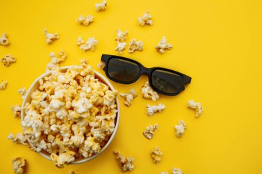 Sarı arka planda patlamış mısır ve 3D gözlüklü bir kase. Üst görünüm