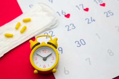 Regl takvimi, çalar saat, hormonal doğum kontrol hapları. Adet dönemi konsepti. Adet sancısı için ağrı kesici.