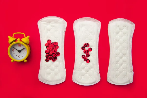 Menstruationspolster mit leuchtend rotem Glitzern und Alarm auf rotem Hintergrund. Frauenperioden Zyklus, Menstruationshäufigkeit. Minimalistisches Konzept der Stillleben-Fotografie — Stockfoto