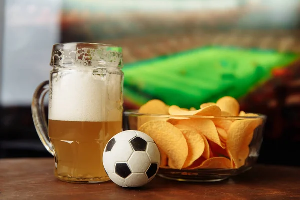 Beer glass, soccer ball and chips in front of tv. Football fans concept