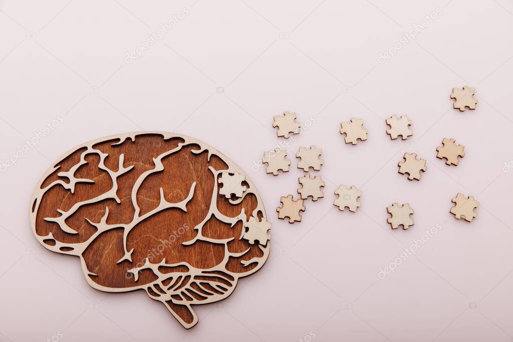 Alzheimers disease and mental health concept. Brain and wooden puzzle on a pink background