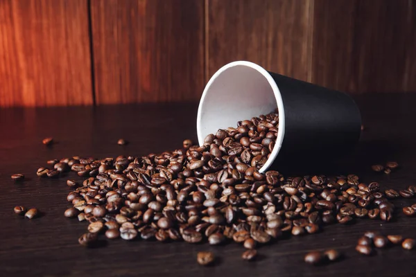 Taza con granos de café marrón en mesa de madera — Foto de Stock