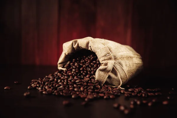 Granos de café dispersos de la bolsa aislados sobre fondo de madera — Foto de Stock