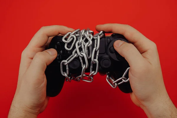 Hands of a young man holds a game controller is tied by chain, concept of game addiction — Stock Photo, Image