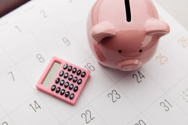 Salvadanaio rosa e calcolatrice su sfondo bianco calendario, risparmio e concetto di investimento. Vista dall'alto — Foto Stock