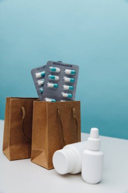 İçinde haplar ve medikal beyaz kaplar olan çantalar. İnternetten alışveriş teması. Dikey resim