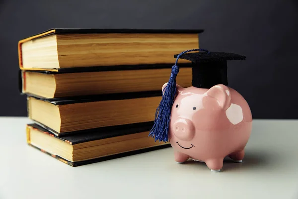 Piggy Bank met hoed en boeken. College, diploma, onderwijsconcept — Stockfoto