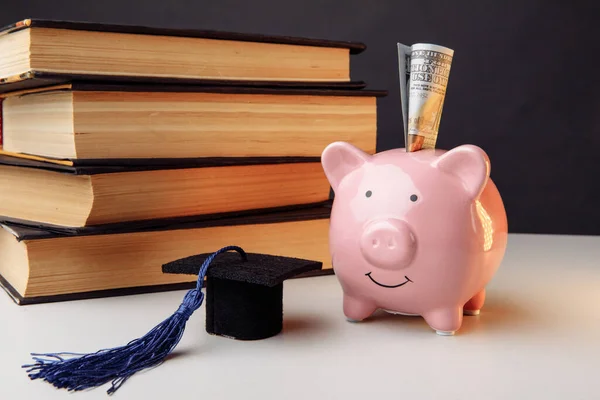 Keramische spaarpot met stapel boeken en pet. College, graduate, onderwijs, spaarconcept — Stockfoto