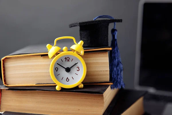 Alarm hodiny, maturitní čepice a knihy na stole Royalty Free Stock Fotografie
