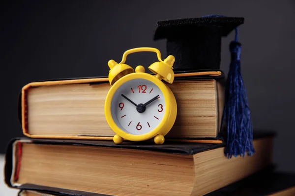 Yellow alarm clock, graduation cap and books on table. Education concept — Stock Photo, Image