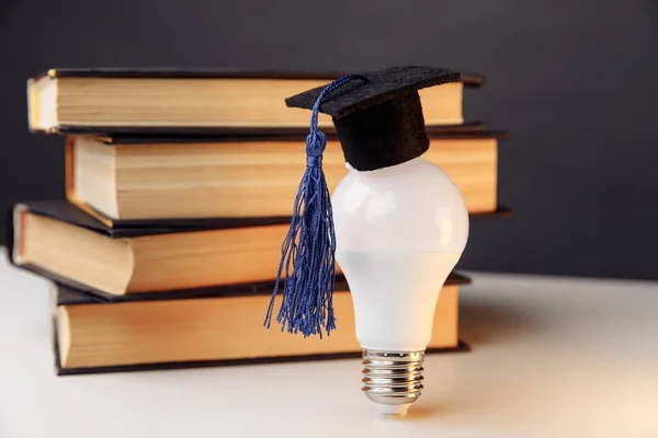 Graduation hat on light bulb with books on a table. Education concept — Stock Photo, Image
