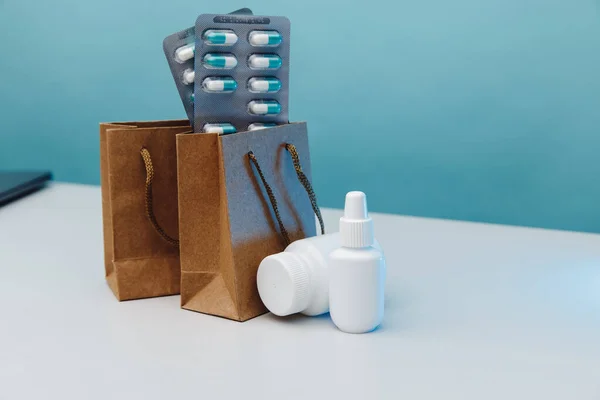 Online shopping theme. Paper bags with medical white containers and pills on blue background — стоковое фото