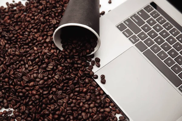 Una taza de café en el portátil y granos de café — Foto de Stock
