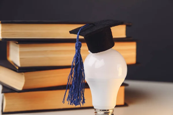 Sombrero de graduación en la bombilla de primer plano con libros. Concepto educativo — Foto de Stock