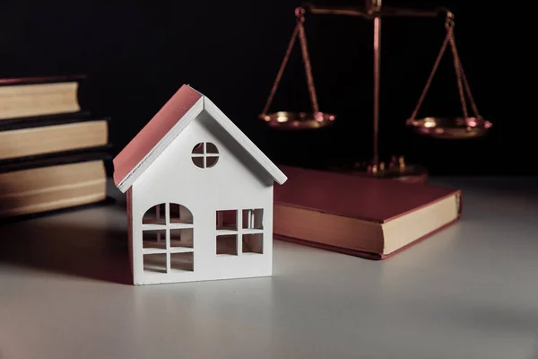 Prodej nemovitosti koncept. Dřevěný model domu a právnické knihy v notářské kanceláři — Stock fotografie