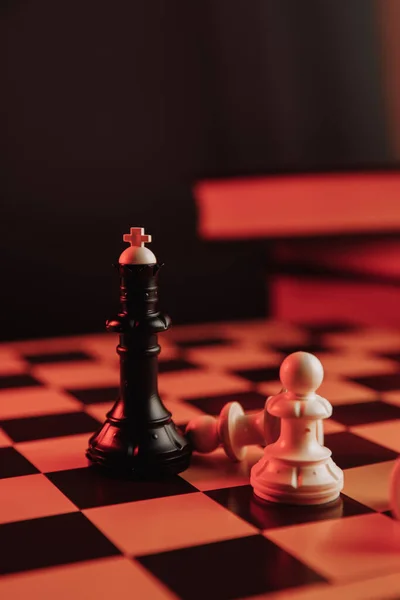 Black king standing on chessboard around falling pawns. Leadership concept. Vertical image — Stock Photo, Image