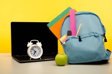 Erzak ve dizüstü bilgisayarla dolu parlak bir sırt çantası. Çevrimiçi eğitim teması