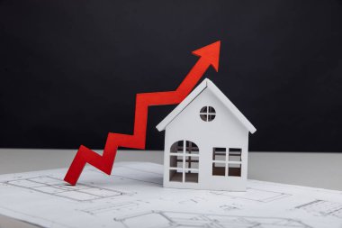 İnşaat maliyeti ve yatırım konsepti. Beyaz ev ve ok üzerine bir çizimle