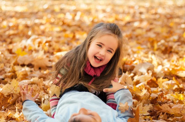 Niños felices en el parque de otoño tumbados sobre hojas —  Fotos de Stock