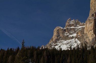 Sella kışın Passo Sella 'nın üstünde Önünde Orman ve Arkaplanda Mavi Gökyüzü