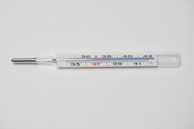 Beyaz yüzeyde cam termometredeki cıva. Tepeden tırnağa kopyalanmış. Grip ya da koronavirüs gibi hastalıklara bağlı yüksek sıcaklığı ölçmek için termometre.