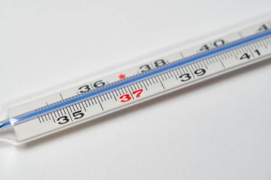 Beyaz yüzeyde cam termometredeki cıva. Tepeden tırnağa kopyalanmış. Grip ya da koronavirüs gibi hastalıklara bağlı yüksek sıcaklığı ölçmek için termometre.