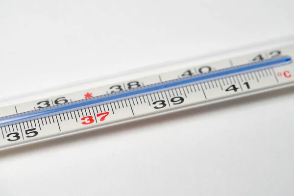 Mercury in glass thermometer on white surface. Copyspace on top and bottom. Fever thermometer in analog form for measuring high temperature due to illness like flu or coronavirus