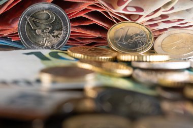İki, iki, ve bir, bir, 1, Avro bozuklukları 10 Euro 'luk banknotların önünde. Altında farklı bozuk paralar odak dışı.
