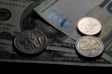 Yarım dolar ve bir ve iki Euro. Yüz, yüz, Avro ve Dolar banknotlarının üstüne. Dolar gölgede, Euro ışıkta