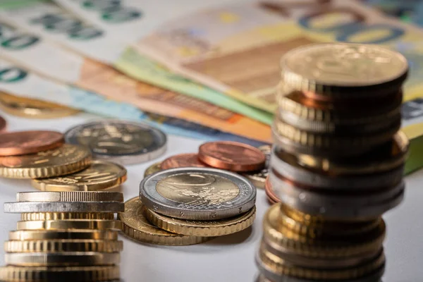 Odaklanmış iki Euro bozuk para, bir yığın Euro. Banknotlar arka planda. Para Birimi ve Değişim Konsepti