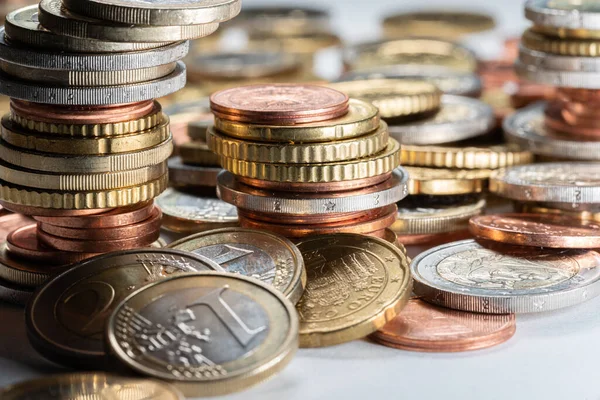 Bunch of Euro coins, stacked coins on white surface. Different coins all over the place