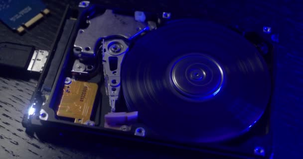 青い光の下で小さなハードドライブにパンニング ノートパソコン用データ記憶装置 — ストック動画