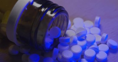 Mavi ışıkta içinde küçük beyaz haplar olan cam şişe. Şişedeki viral enfeksiyon için ilaç.