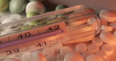 Hap ve ilacın üstüne ateş ölçer. Ateşi ve hastalığı ölçmek için termometre. Ateşi düşürmek için ilaçlar ve antibiyotikler. Klinik termometrede yüksek sıcaklıktan sevgili sıcaklığına geçiş