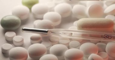 Farklı beyaz haplarda cıvalı cam termometre. Beyaz ve kırmızı ışığın altında ince bir termometre. Soldan sağa hareket