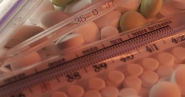 Camdaki civa termometresi maksimum termometre sürümünde. Klinik termometrede kırmızı ışıkta soldan sağa dönen haplar var..
