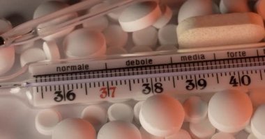 Cam termometrede klinik ilaçlar ve antibiyotikler. Ateş termometresi ve ilacın üzerinde kayma, farklı haplar ve vitaminler.