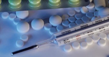 Farklı ilaç hapları ve haplar ve eski cam cıva termometreyle. Antibiyotikler, farklı ağrı kesiciler ve vitaminler içeren klinik termometre.
