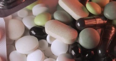 Farklı haplar ve vitaminler, kırmızı ve beyaz ışığın altında, koyu renkli kapsüller ve takviyeler. Farklı tıbbi durumlar için ilaç. Antibiyotikler, farklı şekillerde ağrı kesici.