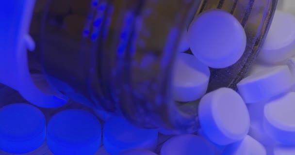 ガラス瓶の中に白い錠剤 多くの小さな錠剤 青い光の下で茶色の瓶の中のオピオイド — ストック動画