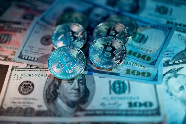 ABD 'den gelen 100 dolarlık banknotlara altın Bitcoin' ler. Kripto para birimi Bitcoin ile Amerika Birleşik Devletleri para birimi. Mavi ışıkla aydınlatılmış