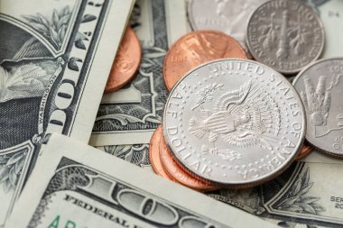 Half Dollar Coin on smaller coins surrounded by Dollar Banknotes. US Economy and Currency. Pile of Cash Money