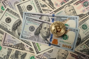 Amerika Birleşik Devletleri 'nden gelen 100 dolarlık banknotların üzerinde Bitcoin para var. Dijital kripto para birimi ve Amerikan doları. Yığınla paranın üzerinde altın parlıyor.