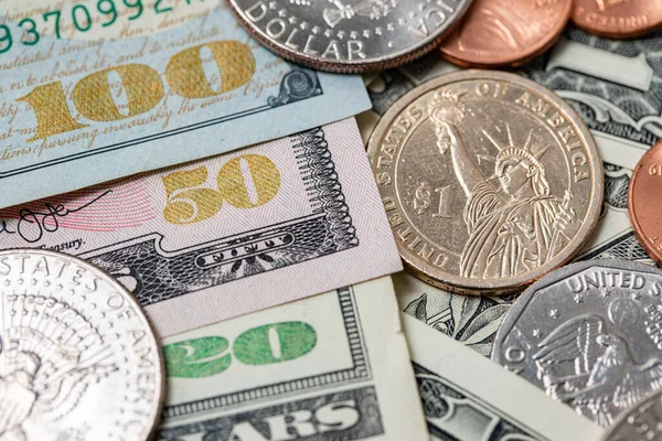Dollar coins and banknotes, US dollar currency. Economy of the United States of America, income and expenses concept. Half dollar and one dollar coin on large denomination banknote