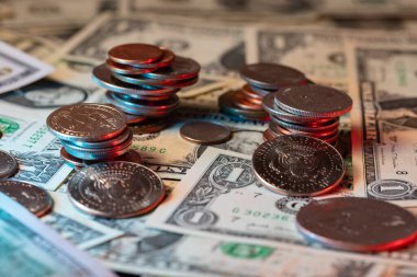 Amerikan doları banknotlarında dolar sikkeleri. Refah için birikmiş madeni paralar. Dolar banknotlarının üzerine yarım dolarlık paralar serpiştirilmiş.